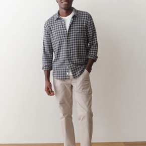 Man wearing a checkered shirt and beige pants against a plain background