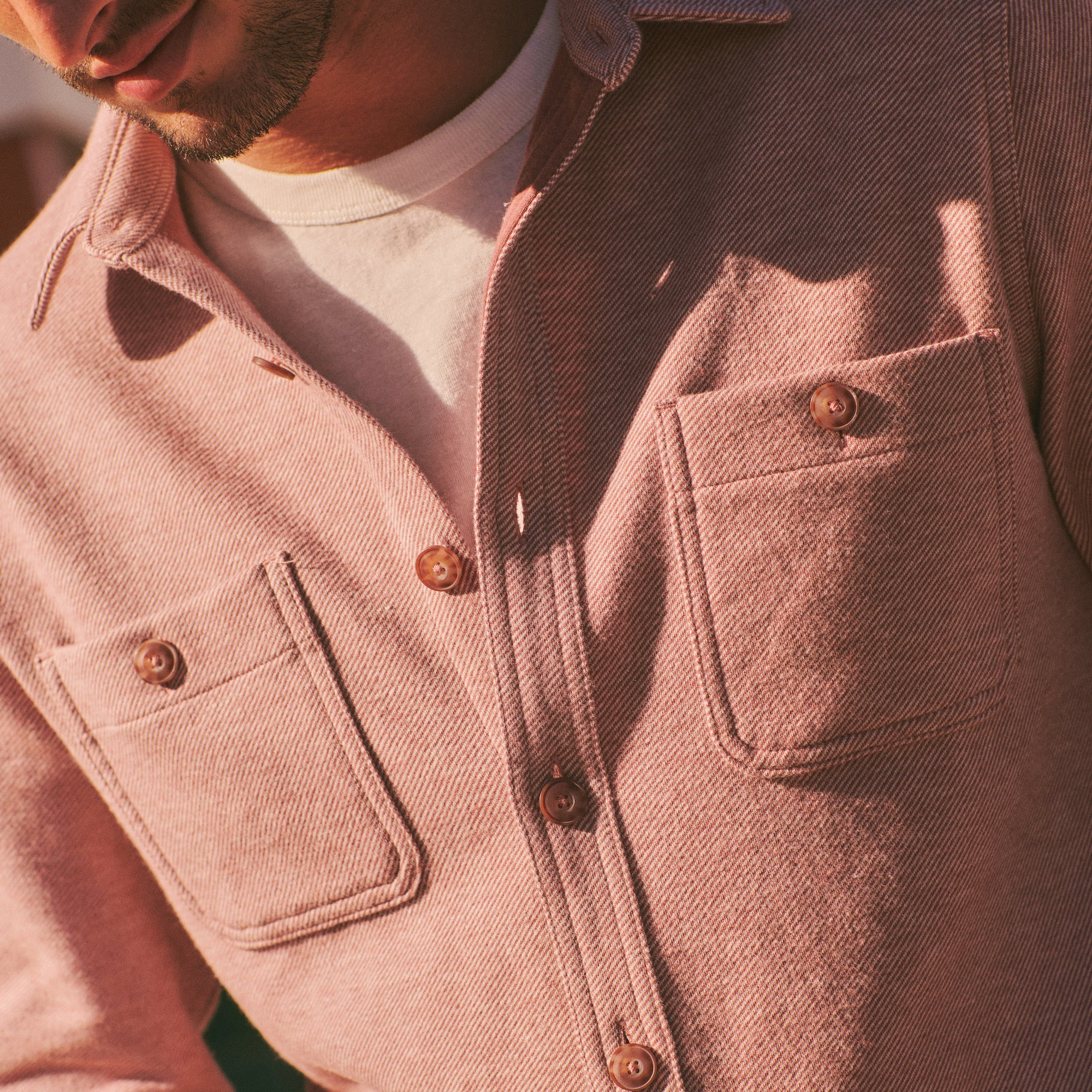 Close-up of a person wearing a pink jacket with button details.