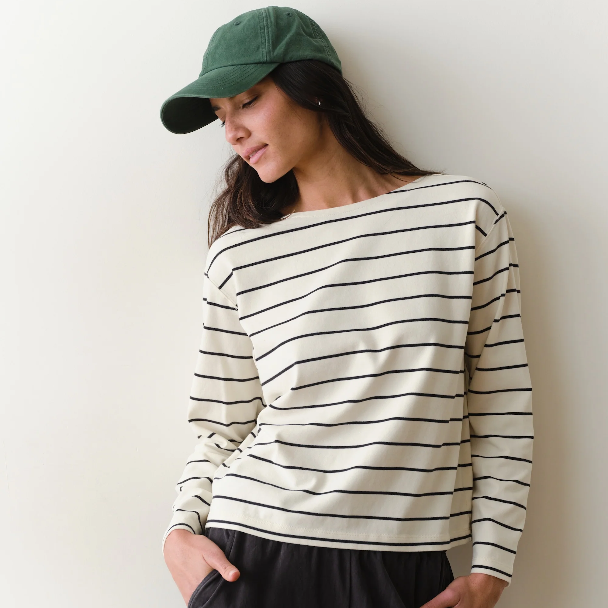 Woman wearing a black and white long sleeved tee on a neutral background.