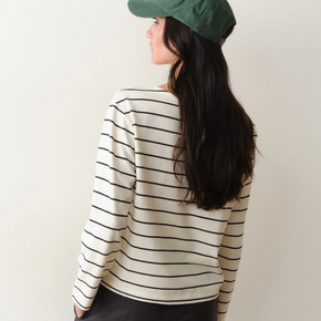 Woman wearing a black and white striped long sleeved tee on a neutral background.