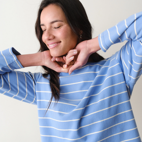 Woman wearing a blue and white striped long sleeved tee with arms outstretched.