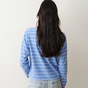 Person wearing a blue striped shirt and light jeans against a plain background