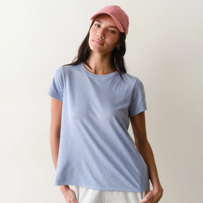 Woman wearing a light blue tee on a neutral background.