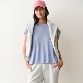 Woman wearing a light blue tee on a neutral background.