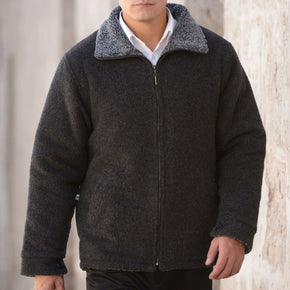 Man wearing a dark gray fleece jacket with a white shirt underneath, standing against a neutral background.