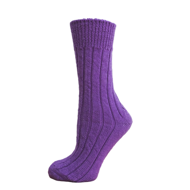 Purple knitted sock on a wooden block with a white background