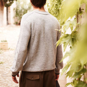 Man wearing a gray sweater walking through a garden