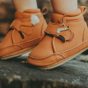 Donsje Plou Fox Shoes - child wearing orange leather high top shoe with fox velcro strap on wooded background