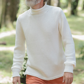 Man wearing white knit sweater and orange pants.