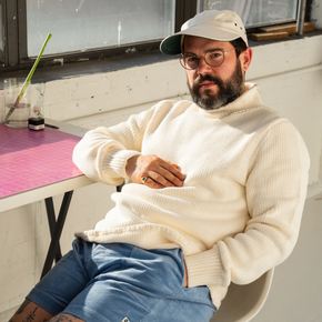 Man wearing white knit sweater and blue shorts.
