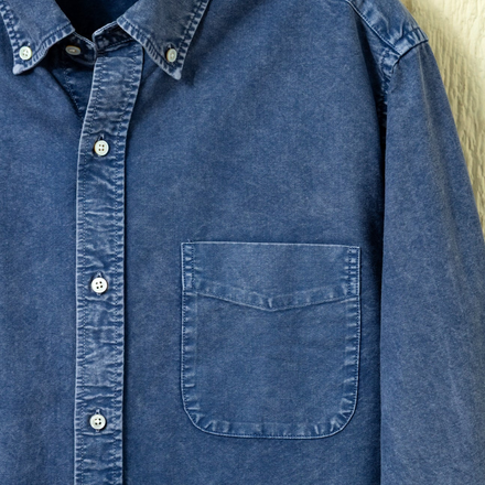 Blue button down shirt on a neutral background.
