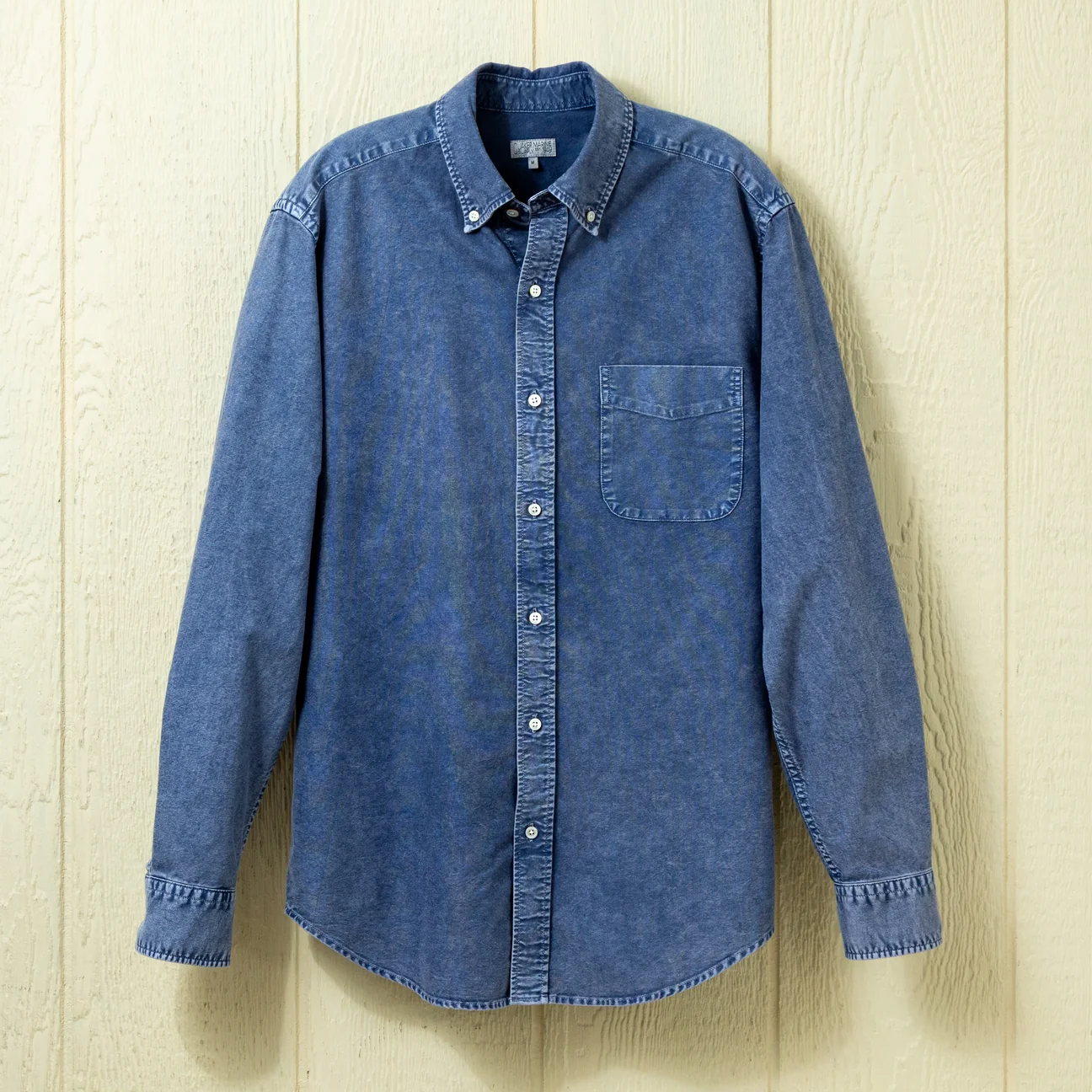 Blue button down shirt on a neutral background.