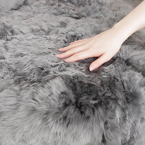 Close-up of a hand touching a fluffy gray rug