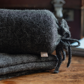 Folded black blanket with a brand tag on a wooden surface