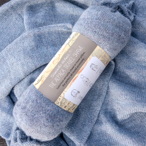 Blue travel shawl with a label on a textured blue background