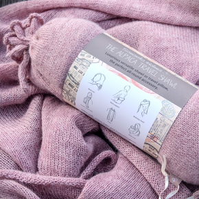 Pink shawl with a label on top, indicating it's a travel pillow and shawl set.