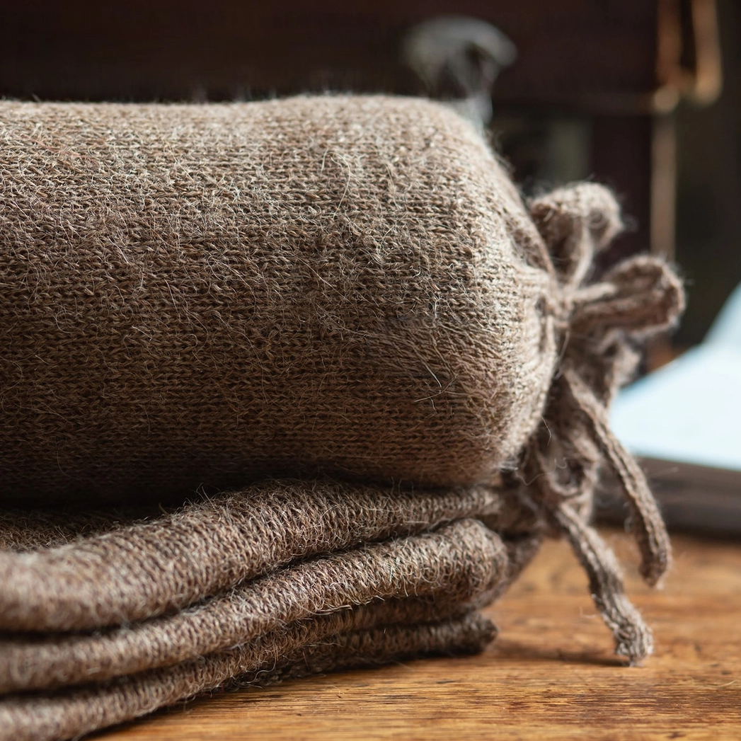 Stack of brown shawls on a wooden surface with a blurred background