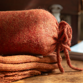 Stack of red shawls on a wooden surface with a blurred background