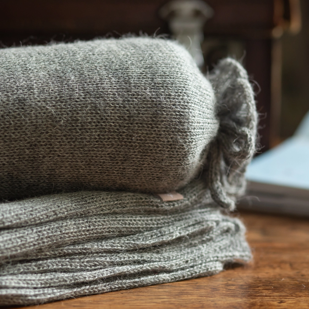 Stack of gray shawls on a wooden surface with a blurred background