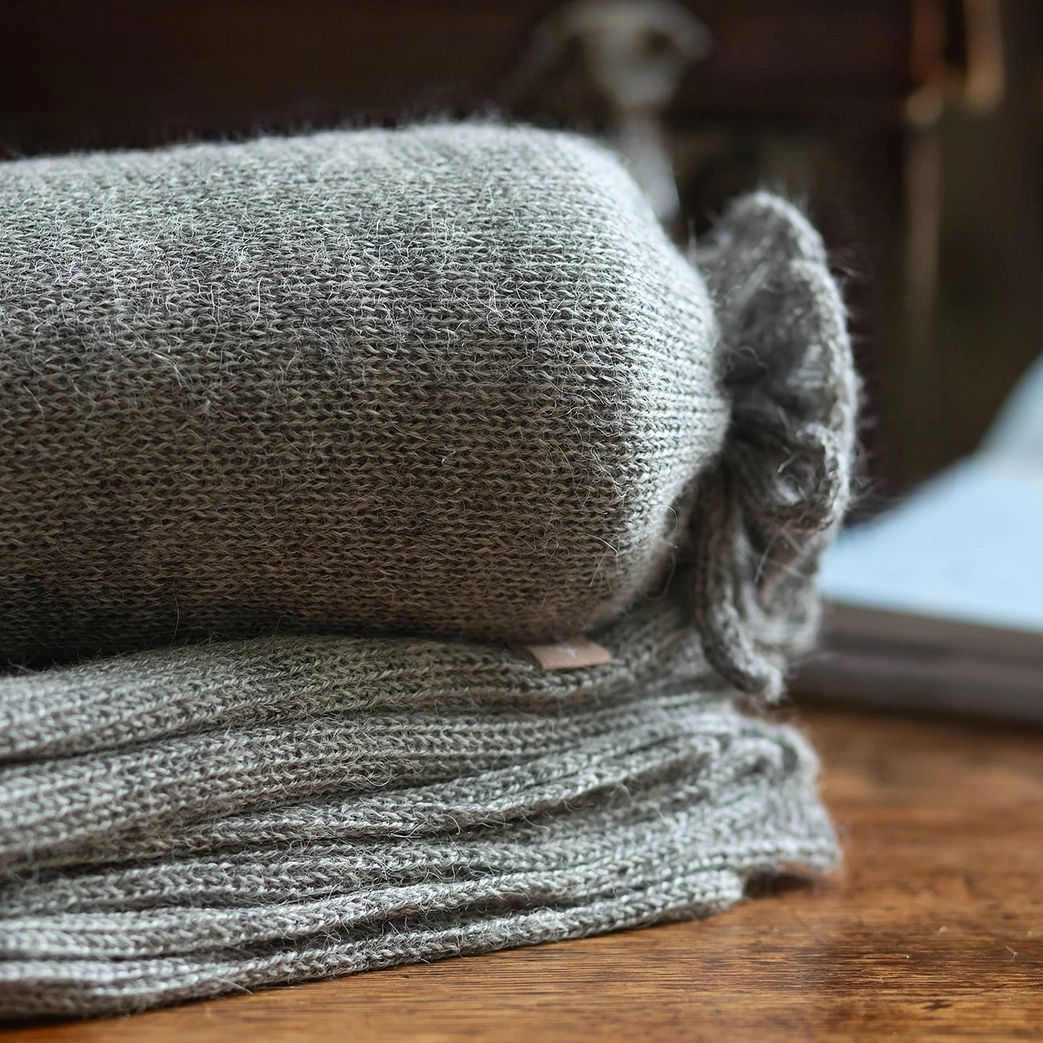 Stack of gray knit fabric on a wooden surface