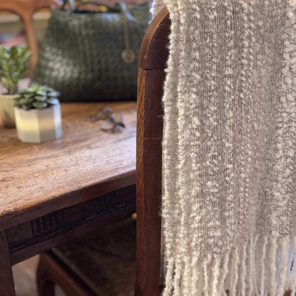 Beige and cream knit scarf hanging over the back of a chair.