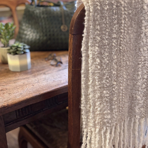 Beige and cream knit scarf hanging over the back of a chair.