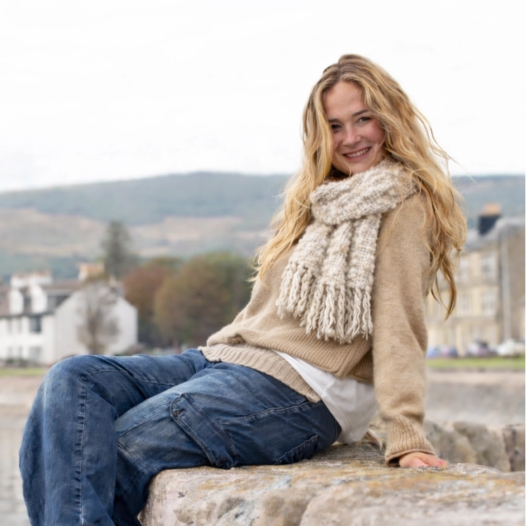 Woman sitting on a stone wall with a scenic background