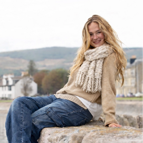 Woman sitting on a stone wall with a scenic background