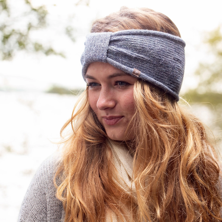 A woman wearing a dusty blue knitted alpaca headband.