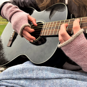 Person playing an acoustic guitar with a scenic background