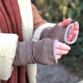 Person wearing brown fingerless gloves with a blurred outdoor background