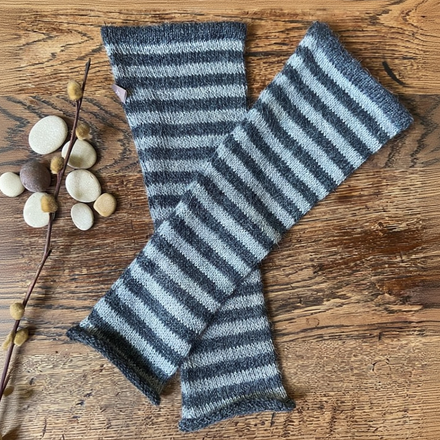 Striped knitted mittens on a wooden surface with decorative elements.
