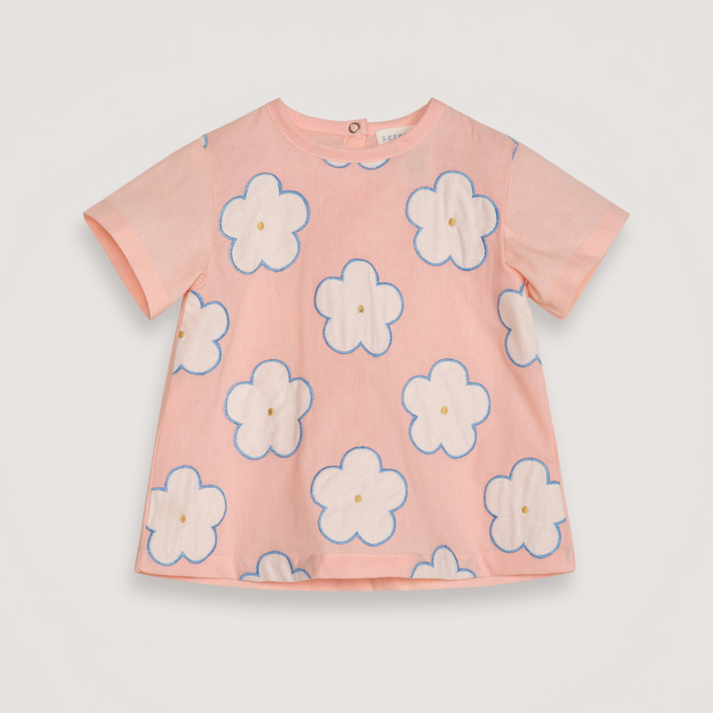 Pink t-shirt with white floral patterns on a light gray background