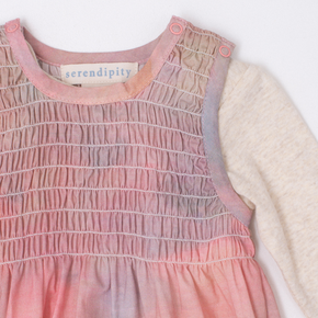 Pink smocked onesie with 'serendipity' label on a white background