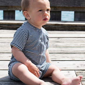 Baby sitting on a wooden dock by the water
