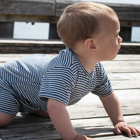 Baby in a striped outfit crawling on a wooden surface