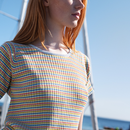 Person wearing a colorful striped shirt with a clear blue sky background