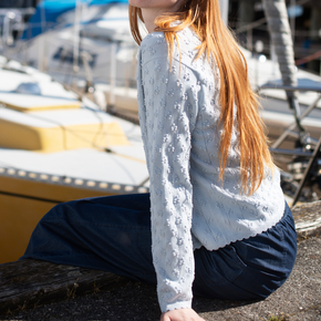 Person wearing a light blue sweater sitting by boats