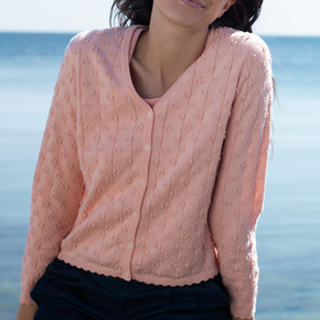 Person wearing a pink patterned sweater with a blurred ocean background