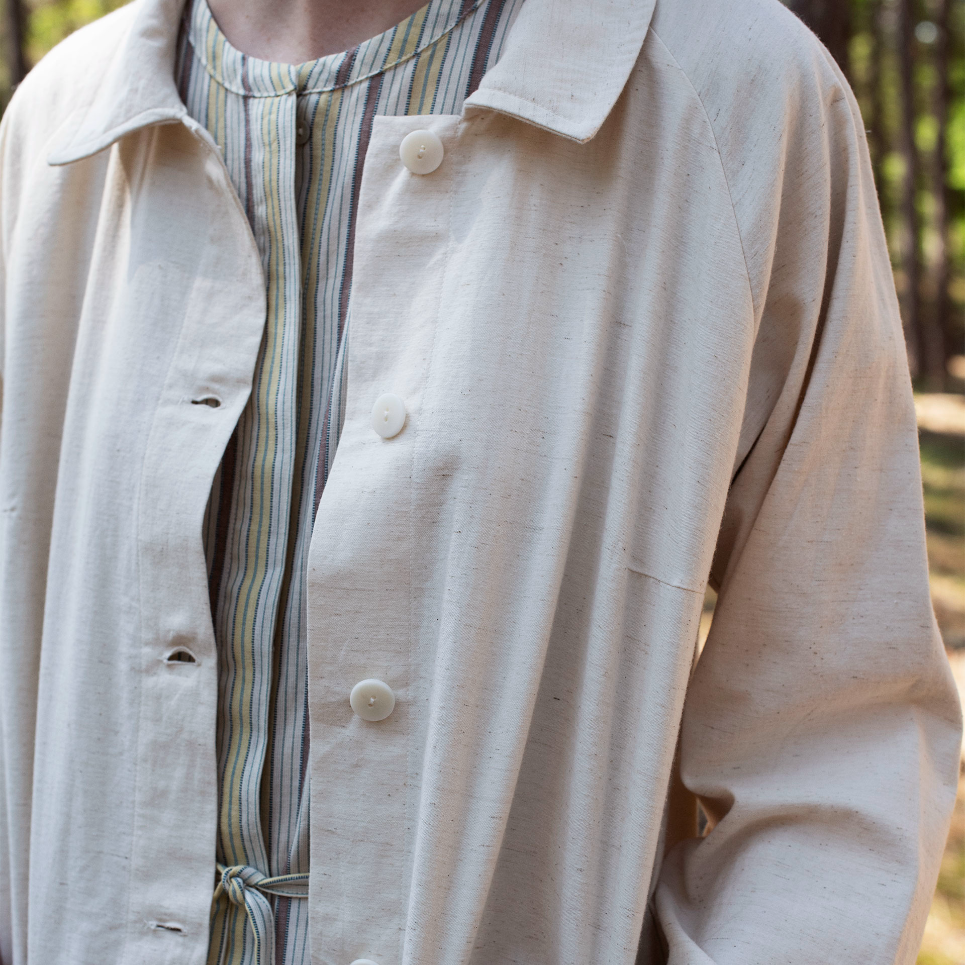 Person wearing an off white jacket with a blurred background