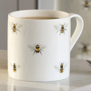 White mug with bee illustrations on a blurred kitchen background