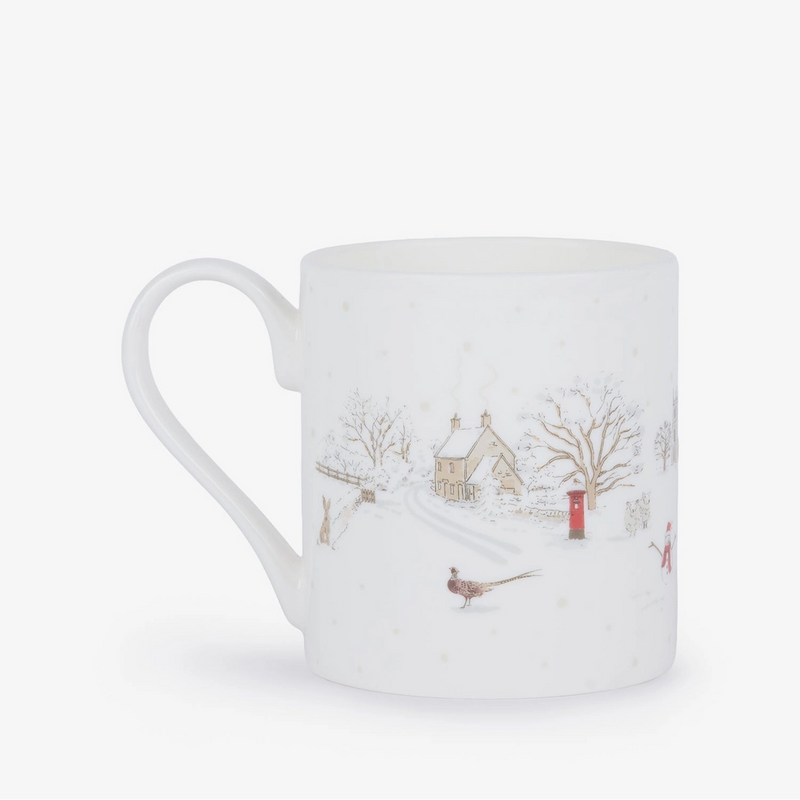 A white china mug featuring a delicate winter village illustration with snow-covered trees, a small house, a red post box, and a pheasant, set against a plain white background.