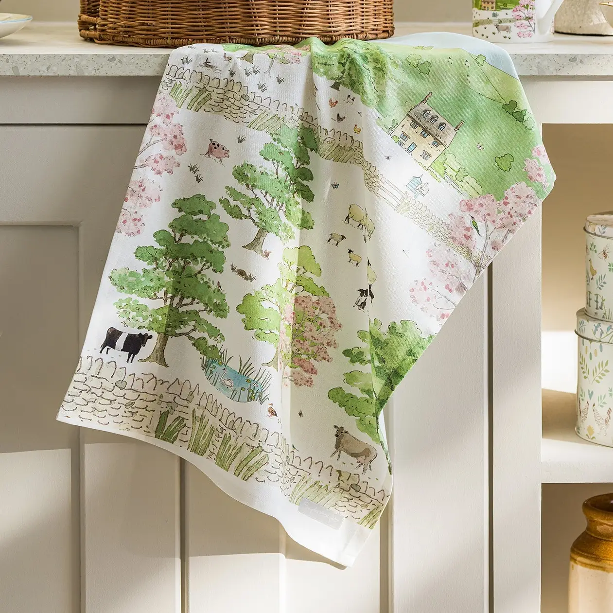 Decorative kitchen towel with farm scene design on a white cabinet.