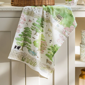 Decorative kitchen towel with farm scene design on a white cabinet.