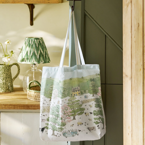Tote bag with a scenic design hanging on a hook in a room with a lamp and decor.