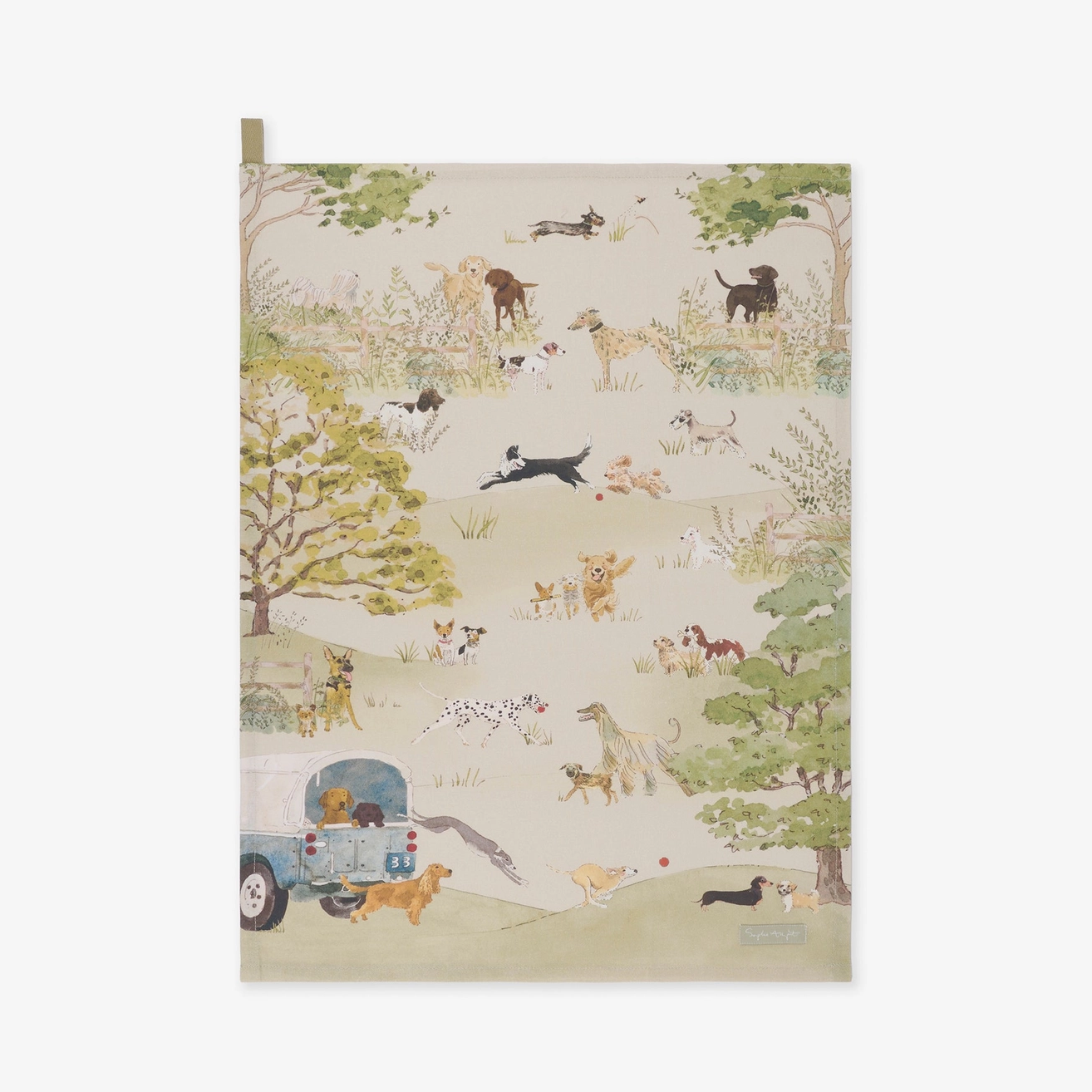 A tea towel featuring a whimsical illustrated scene of dogs, birds, and a blue trailer in a grassy landscape, shown against a plain light background.