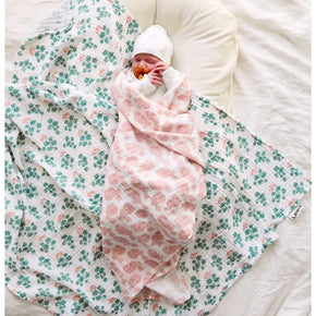 Baby Swaddle - baby swaddled in white baby swaddle with light pink bunny print on a neutral background