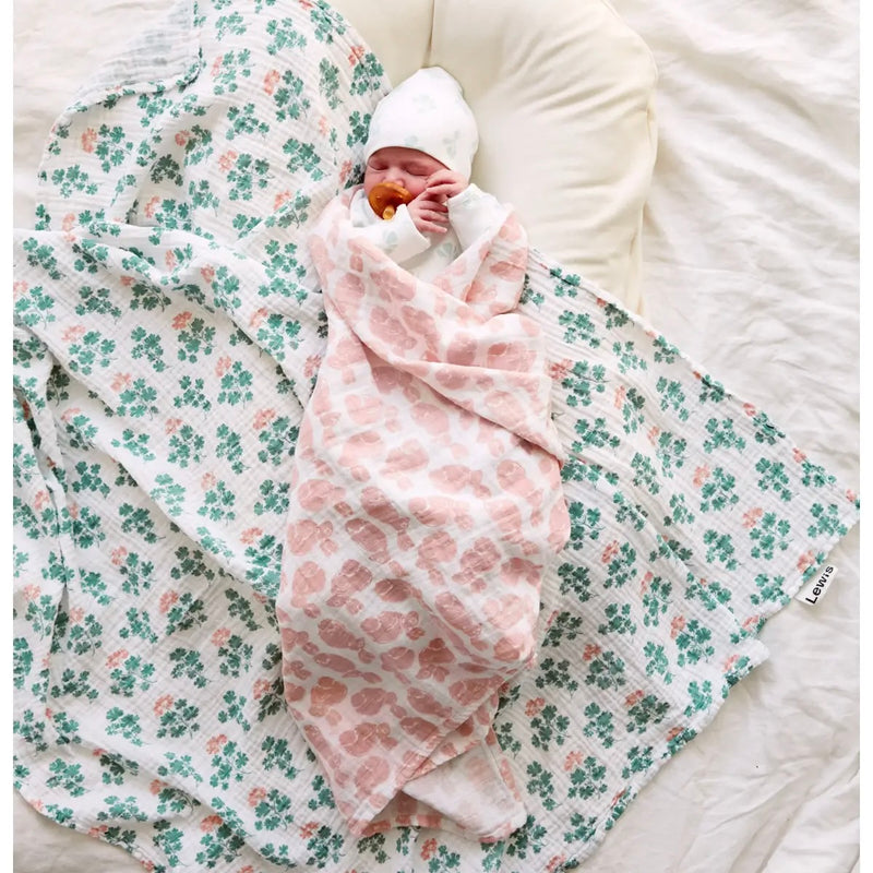 Baby Swaddle - baby swaddled in white baby swaddle with light pink bunny print on a neutral background