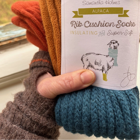 Alpaca rib cushion socks held by a hand with a visible brand label.