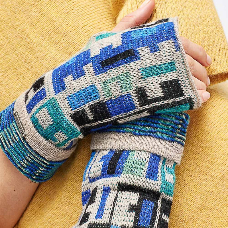 Kuna Wadja Alpaca Gloves - model wearing blue and white geometric patterned gloves on a neutral background